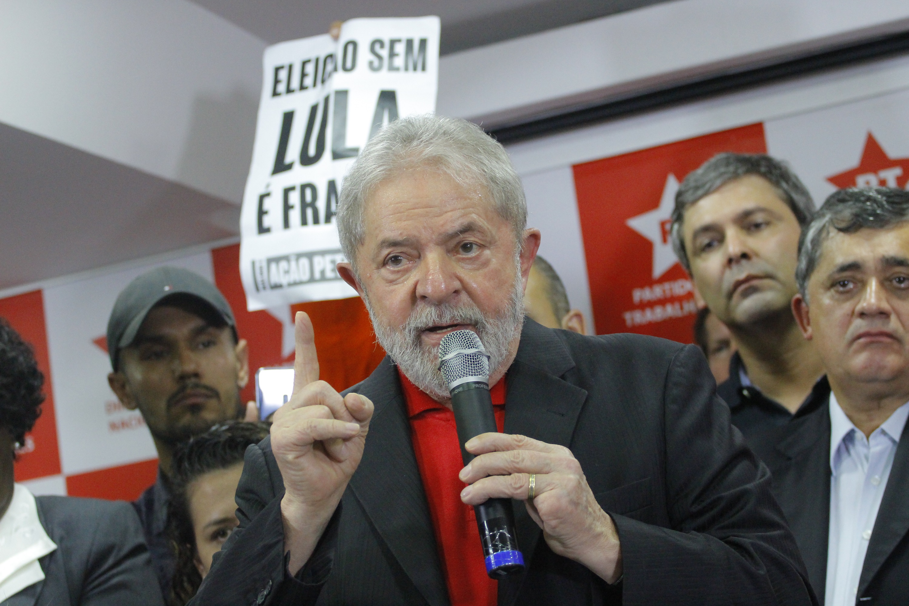 Lula da Silva discursa em evento com banner político