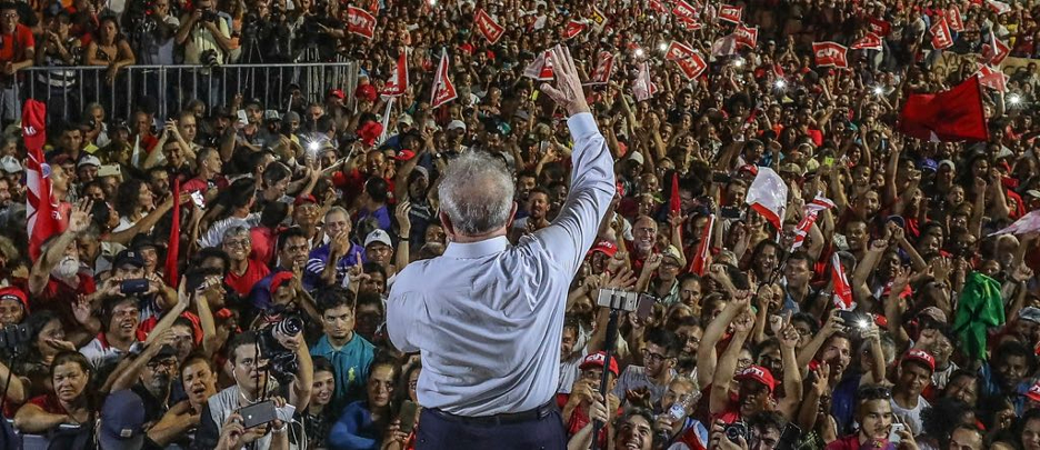 Lula acena à multidão em ato político vibrante.