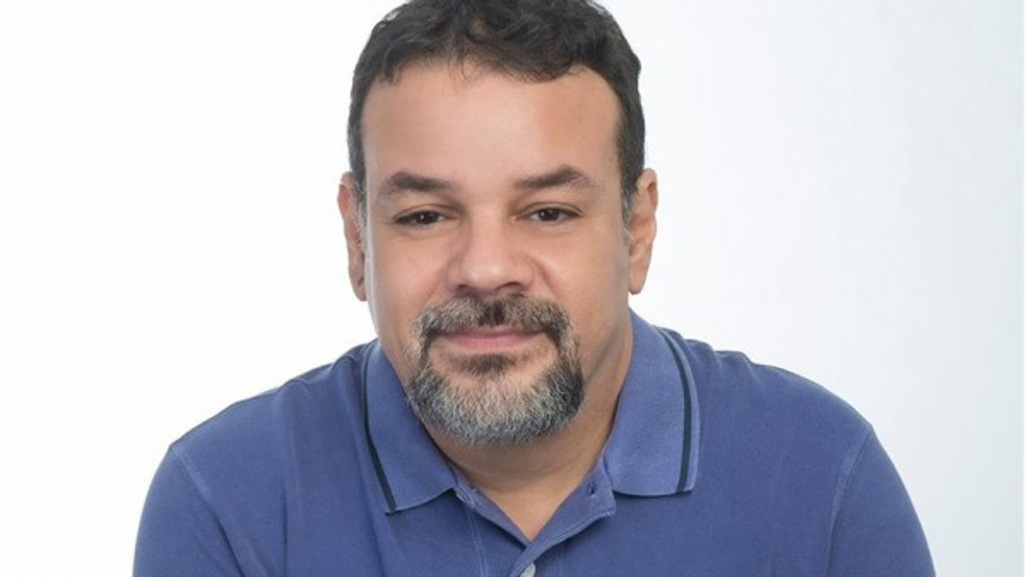 Retrato de homem sorridente com barba em camisa polo azul
