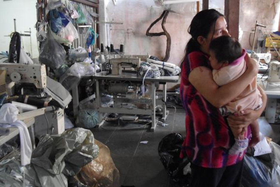 Mãe e bebê em oficina têxtil informal