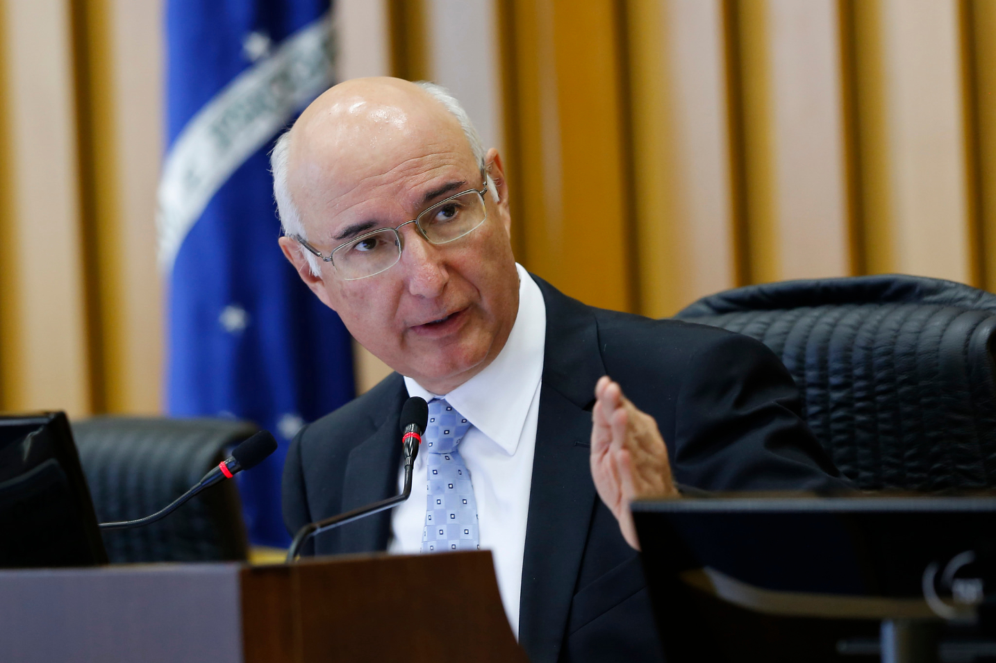 Homem careca de óculos em discurso oficial.