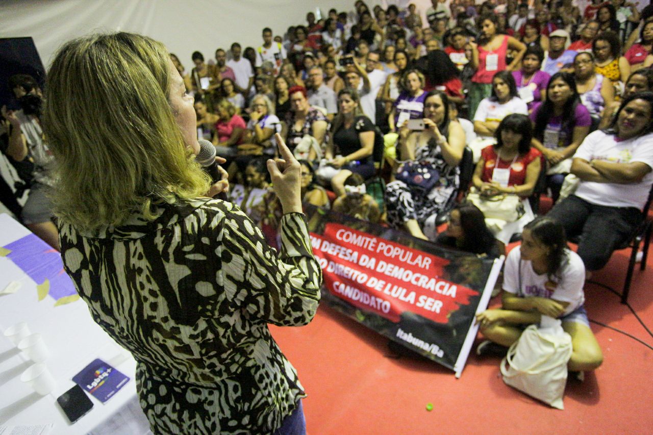 Mulher discursa para plateia em evento político pró-democracia