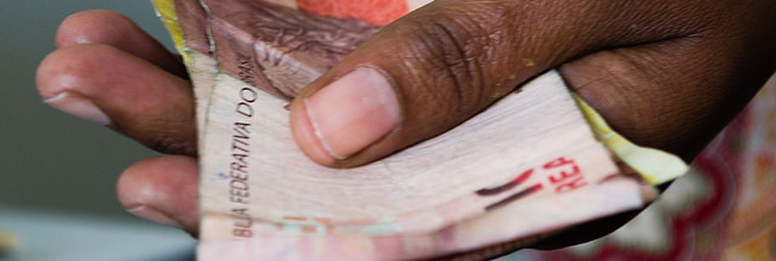 Mão Segurando Notas de Real: Economia e Cidadania