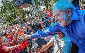 Lula cumprimenta multidão em evento público de grande apoio.