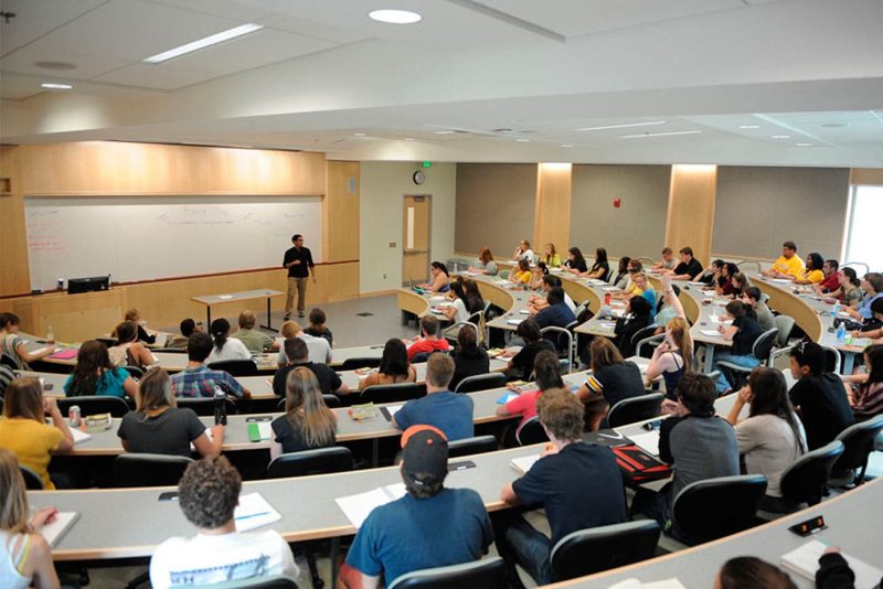 Sala de aula universitária moderna com alunos e professor