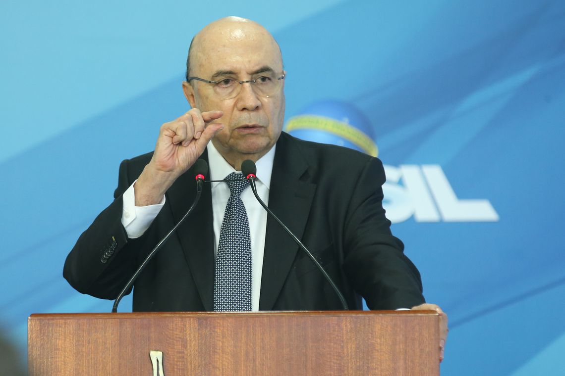 Homem de Terno Gesticula em Púlpito com Fundo Brasil