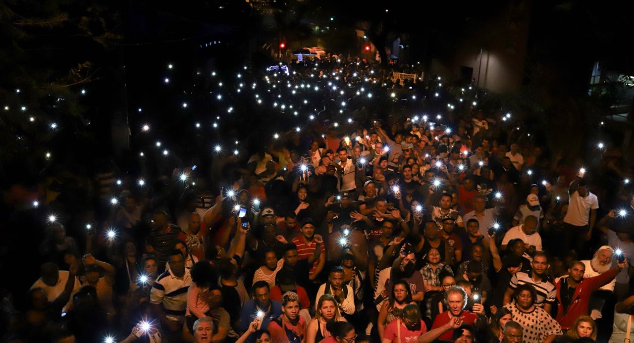 Multidão Noturna Iluminada por Celulares em Ato Público