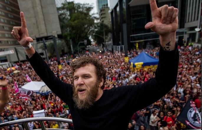 Líder em manifestação popular com multidão e sinal de "L"