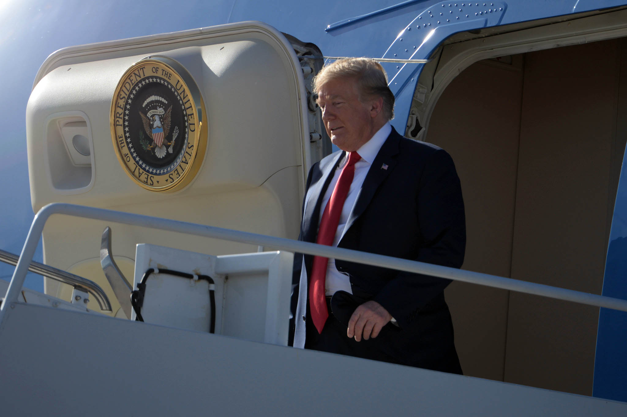 Donald Trump saindo de aeronave oficial com selo presidencial