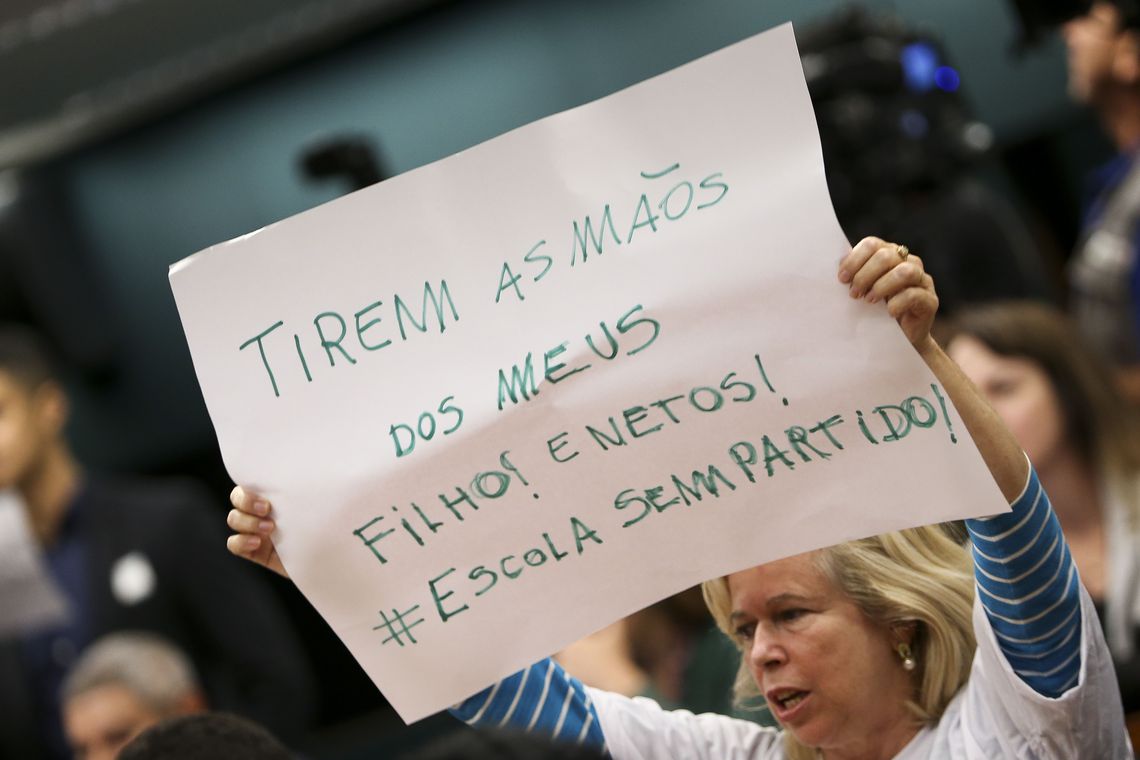 Mulher protesta contra "Escola Sem Partido" com cartaz.