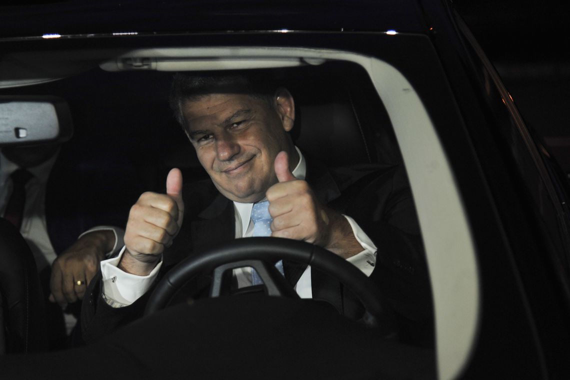 Líder Político Otimista em Carro: Sinal de Positivo