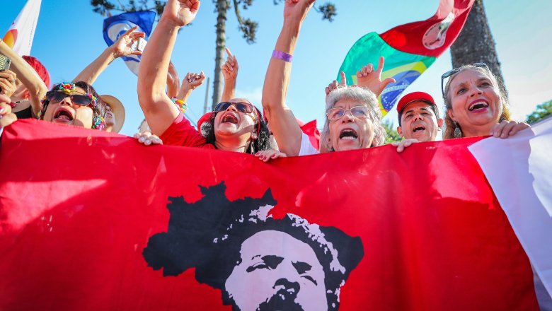 Mulheres ativistas exibem bandeira de Lula e Brasil em ato.