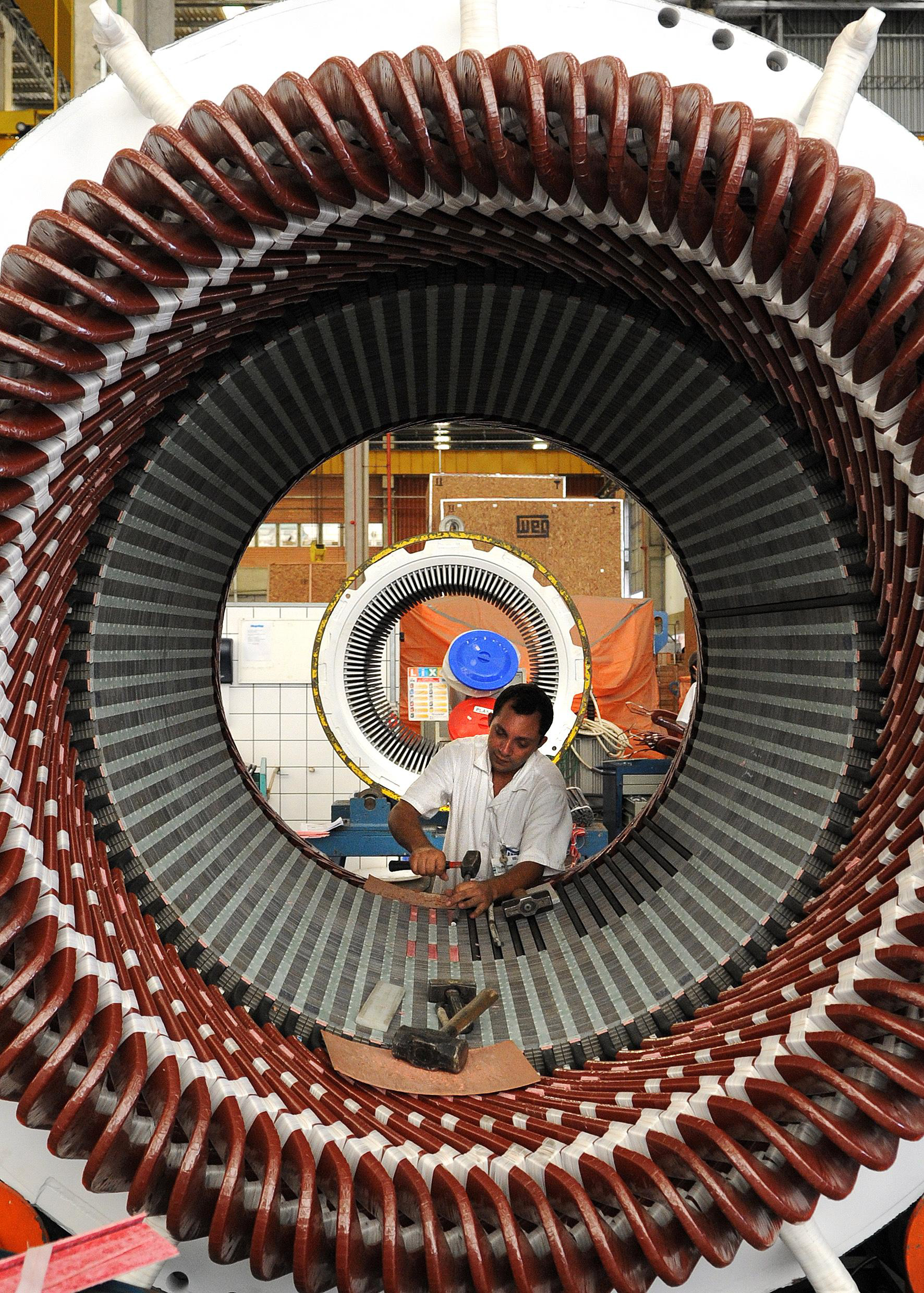 Trabalhador montando bobinas de motor elétrico industrial