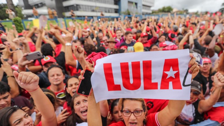 Multidão em apoio a Lula com punhos erguidos e banner