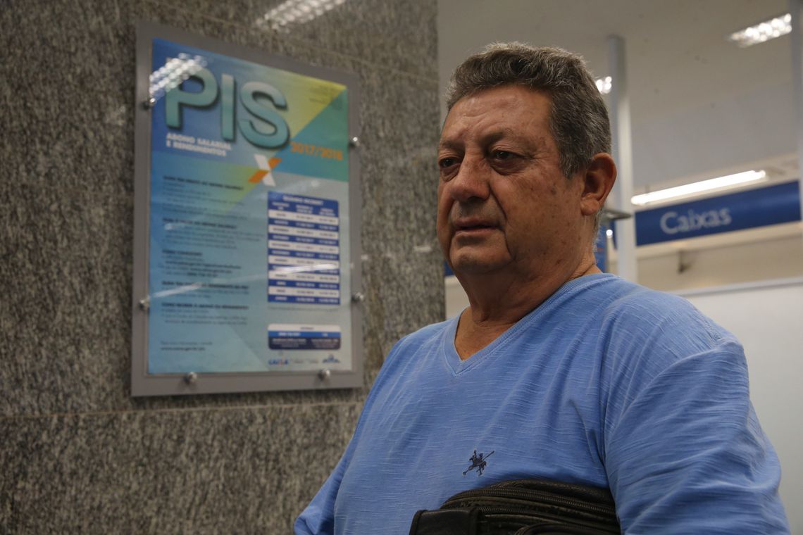 Homem aguarda atendimento em ambiente de agência com cartaz PIS