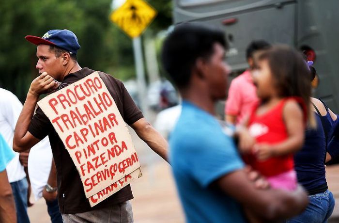 Homem com cartaz busca trabalho e sustento.