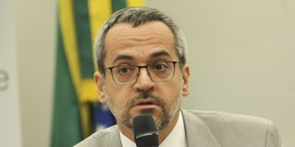 Homem com óculos e microfone em evento formal