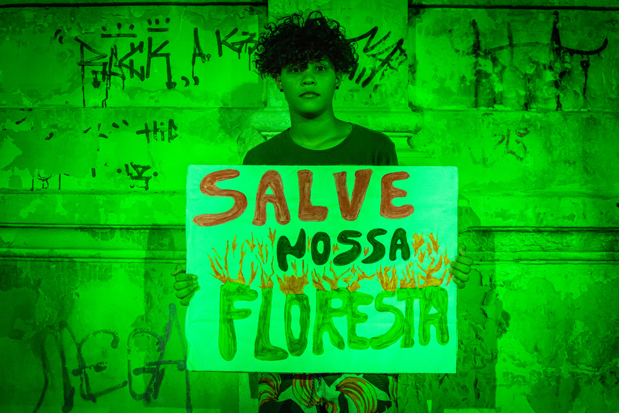 Jovem Ativista Pede 'Salve Nossa Floresta' em Cenário Verde Urbano