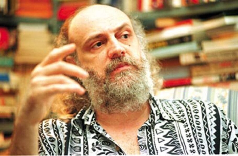 Homem barbudo pensativo em frente a livros