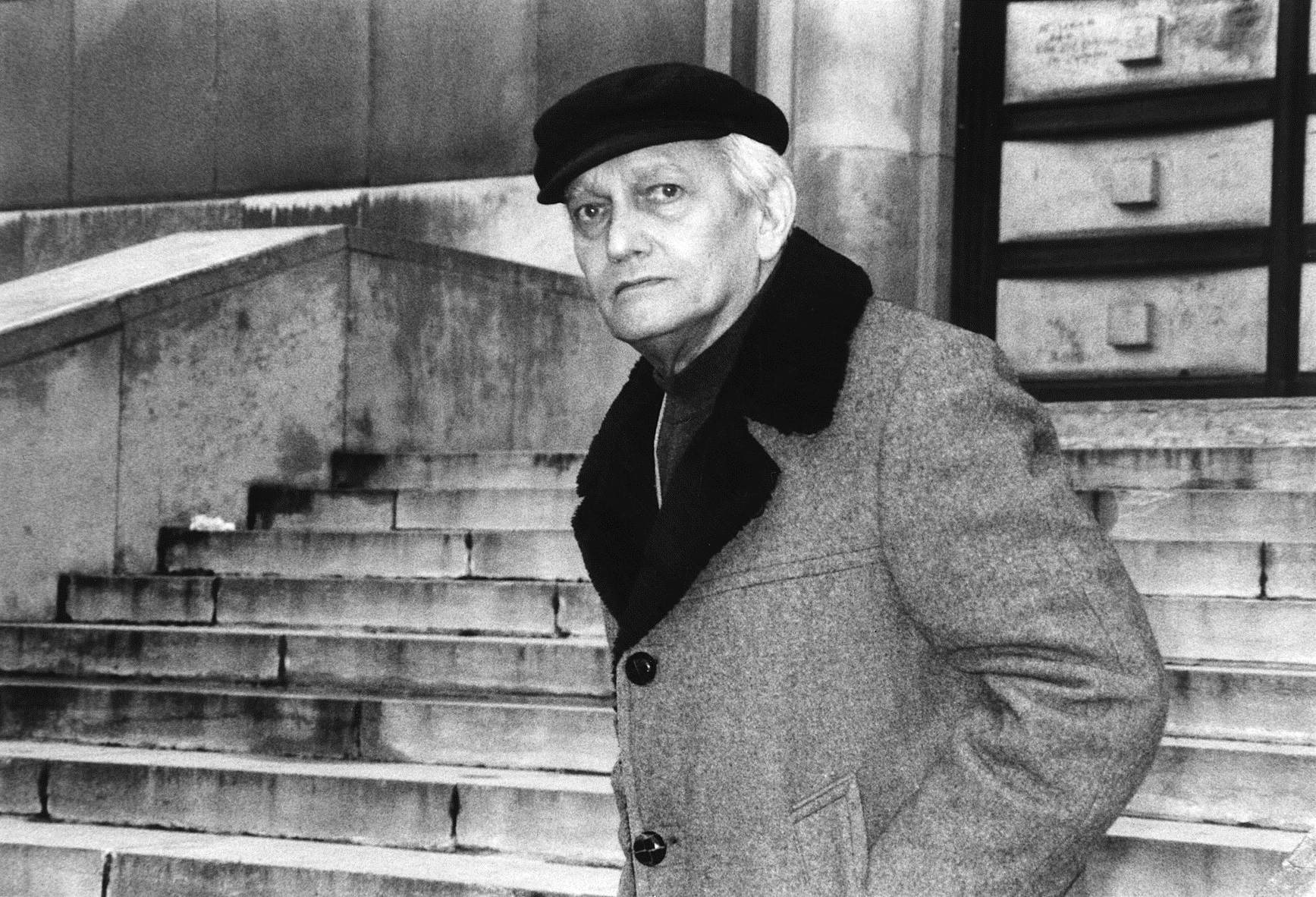 Retrato de Homem Idoso com Boina e Casaco em Cenário Urbano