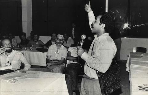 Homem faz "joinha" ao microfone em reunião