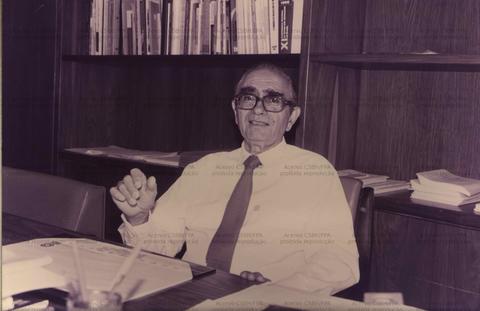 Homem sorridente em escritório com livros