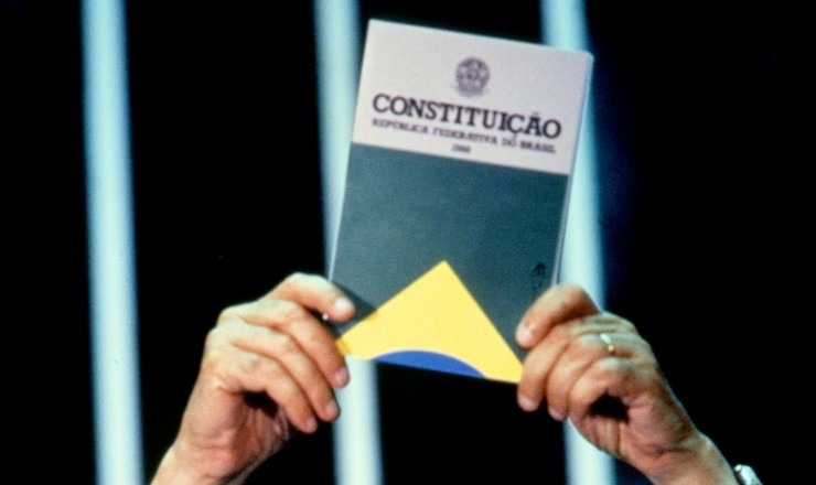 Mãos Erguendo a Constituição Federal de 1988