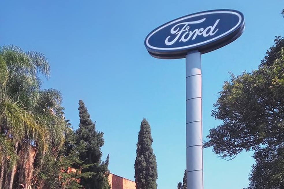 Logotipo Ford contra céu azul e árvores