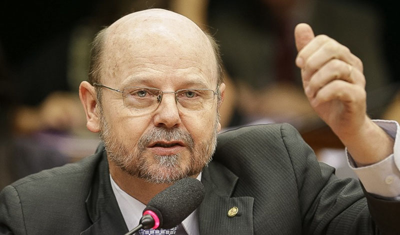 Homem barbudo com óculos discursa e gesticula