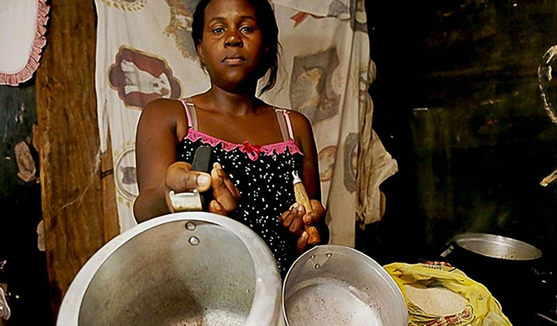 Mulher, cozinha humilde e panelas: o sustento diário