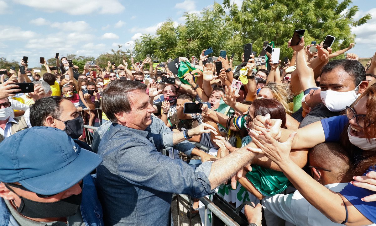 Bolsonaro em meio a apoiadores entusiasmados com celulares