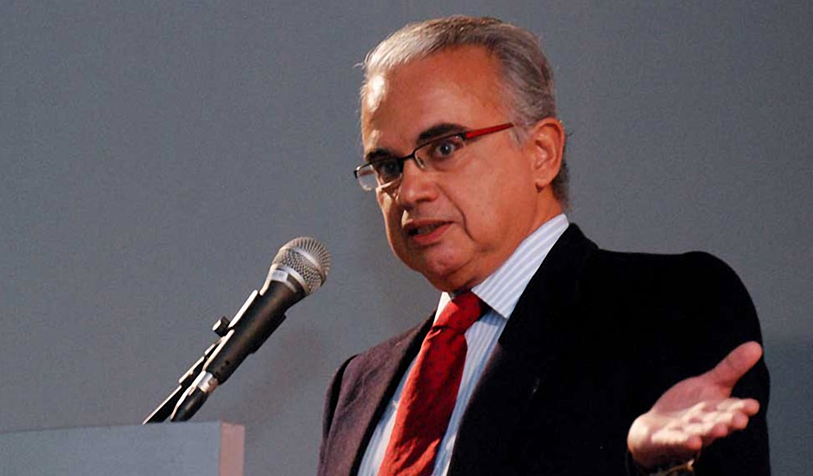 Homem discursando em evento formal com microfone