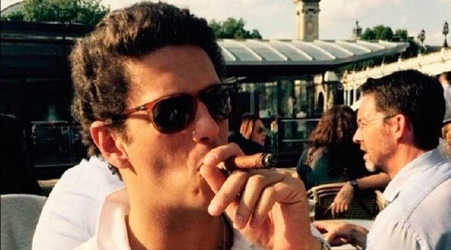 Jovem fuma charuto em ambiente externo e sofisticado