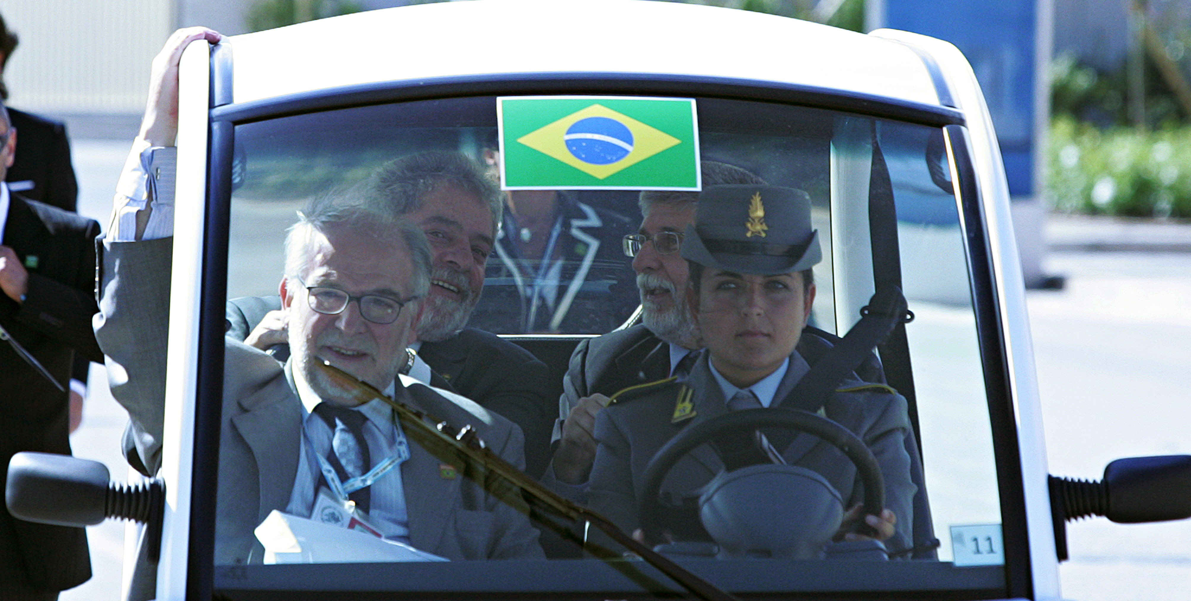 Lula e comitiva em veículo com bandeira brasileira