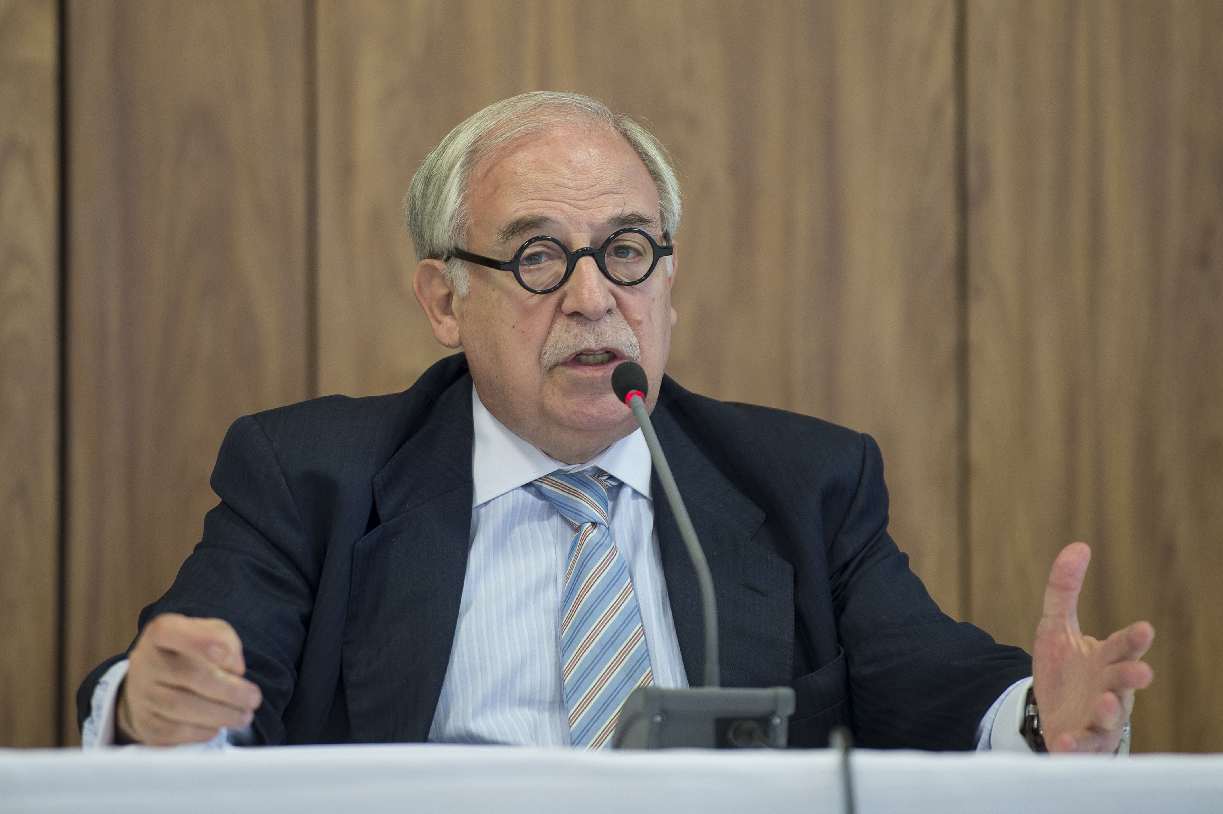 Homem sênior discursa em evento formal com microfone