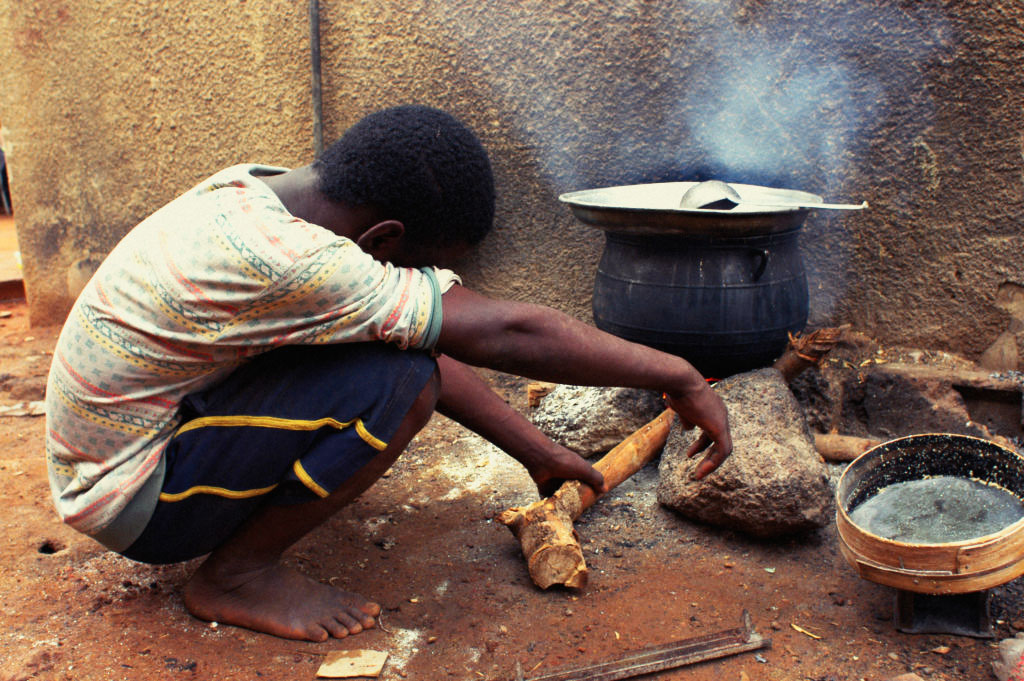 Jovem cozinhando em fogão a lenha artesanal