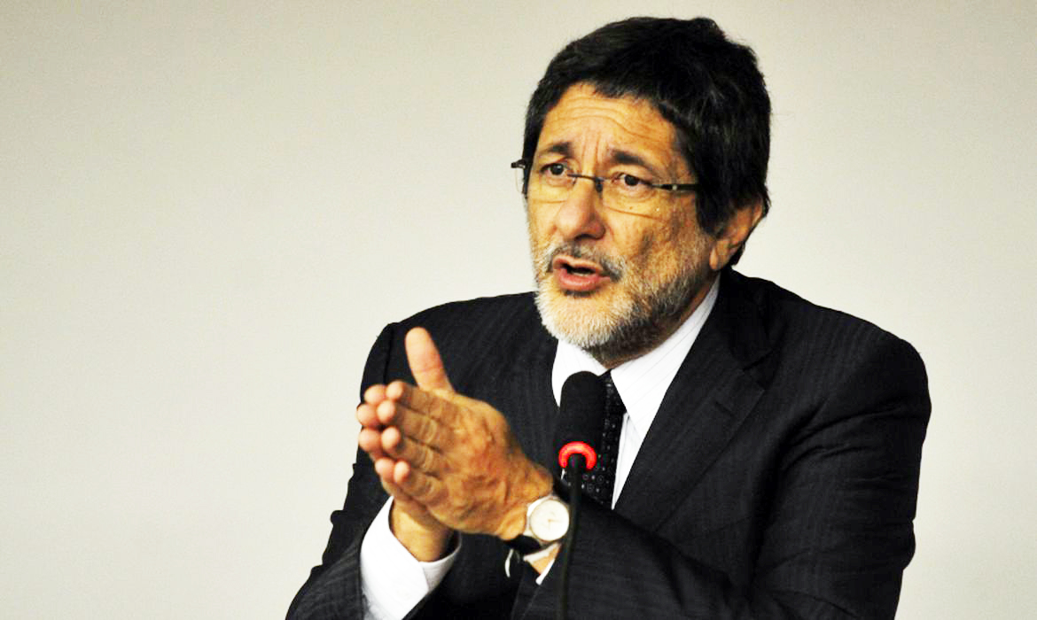 Homem discursando em evento formal com microfone