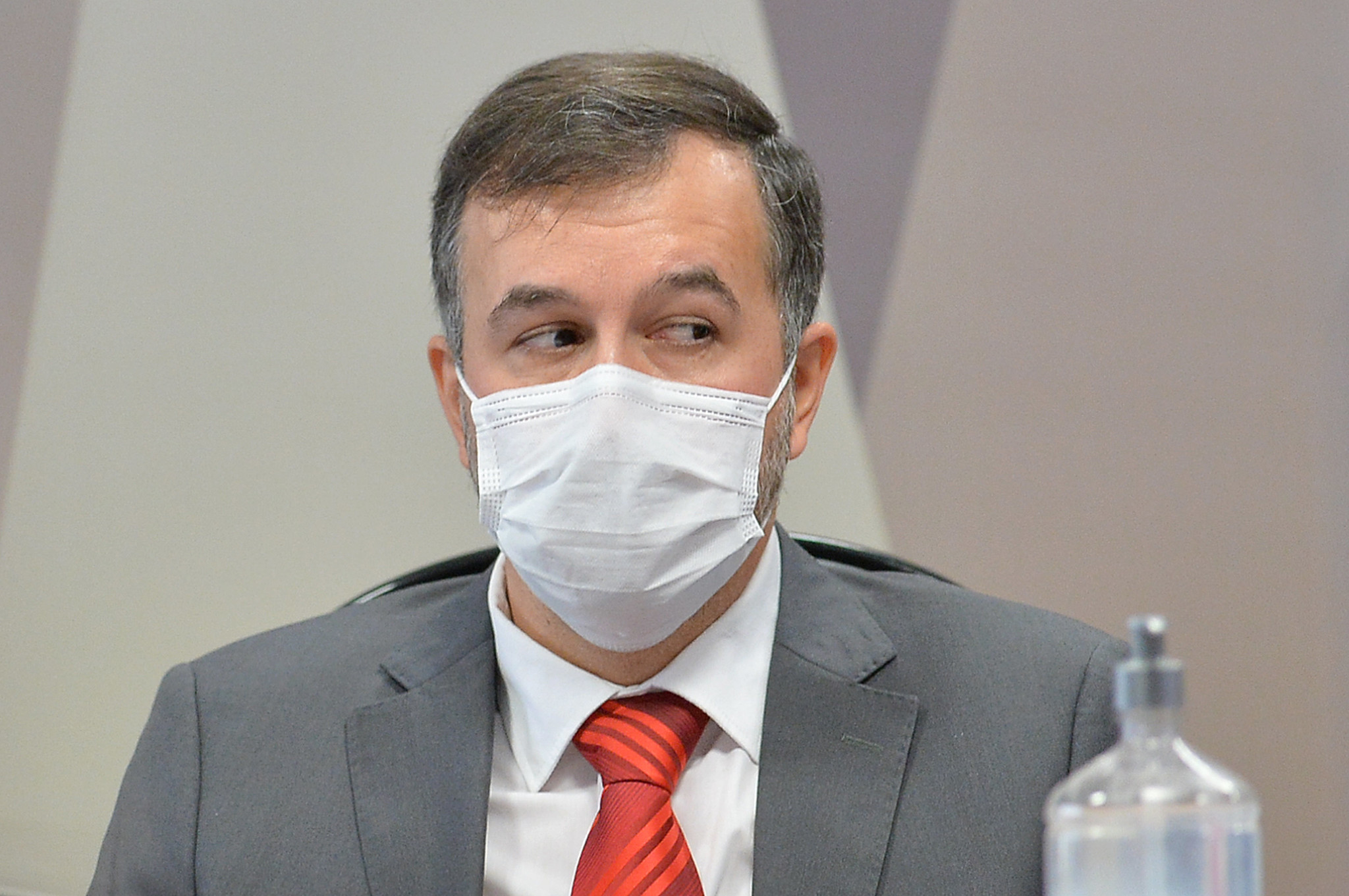 Homem de terno e máscara em contexto formal