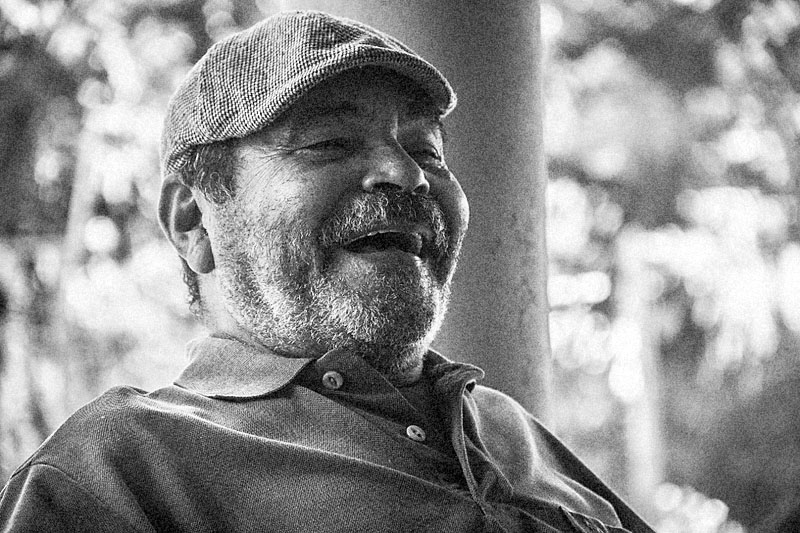 Rosto de homem sorrindo com boné e barba