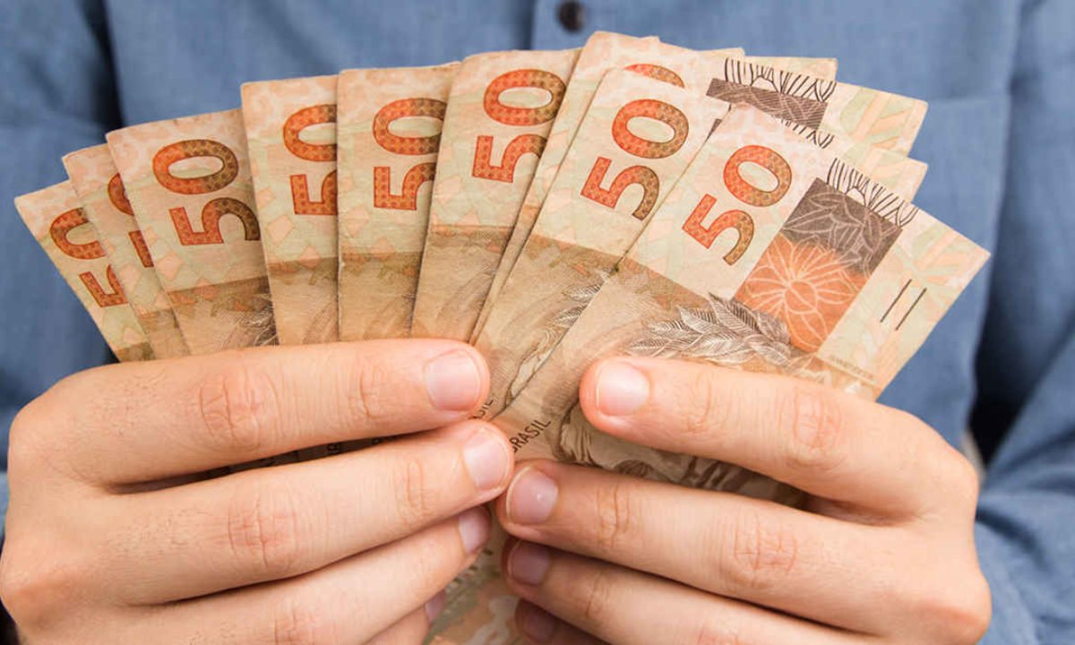 Mãos Segurando Notas de 50 Reais Brasileiros