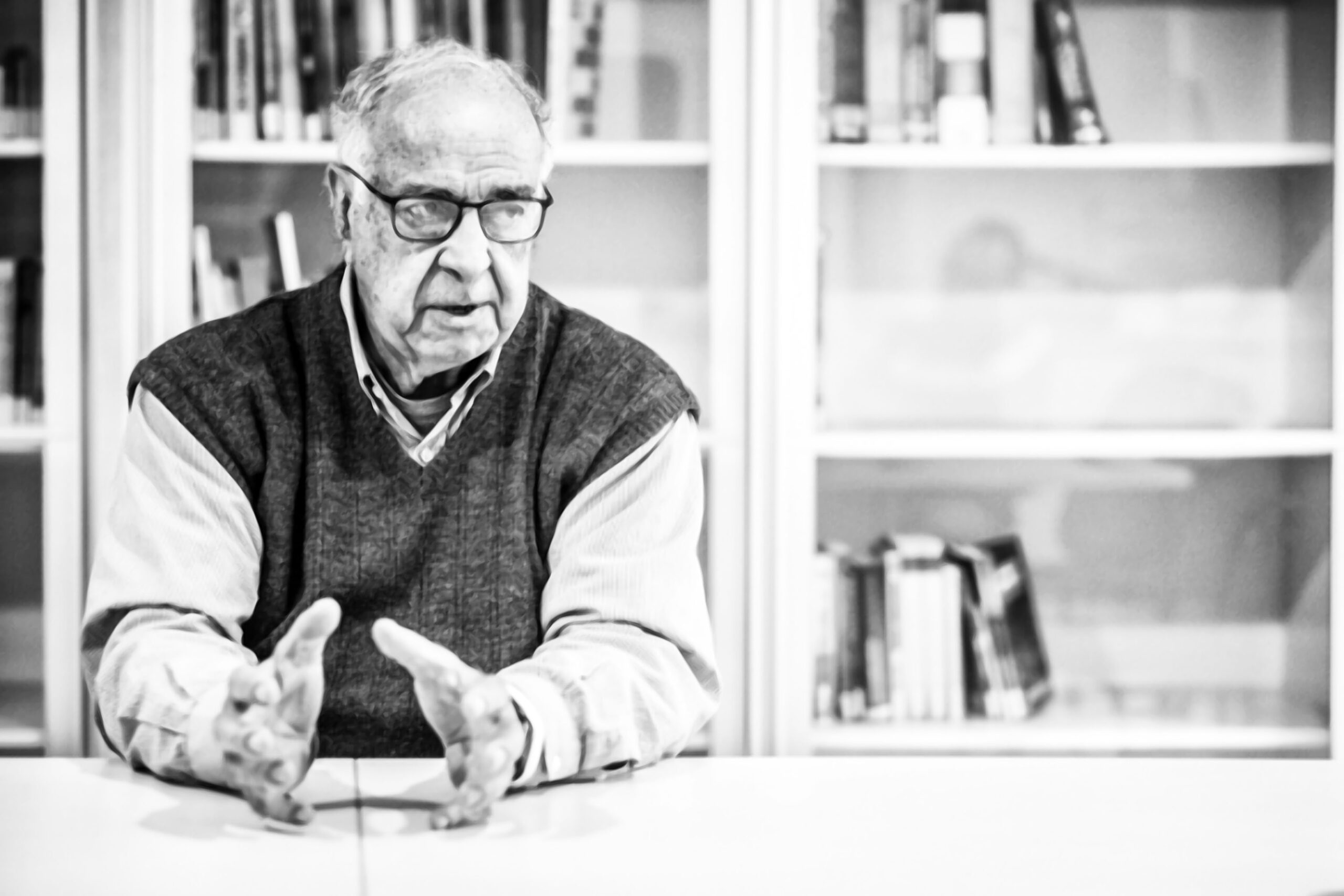 Homem Sênior Gesticulando com Expressão Séria em Biblioteca