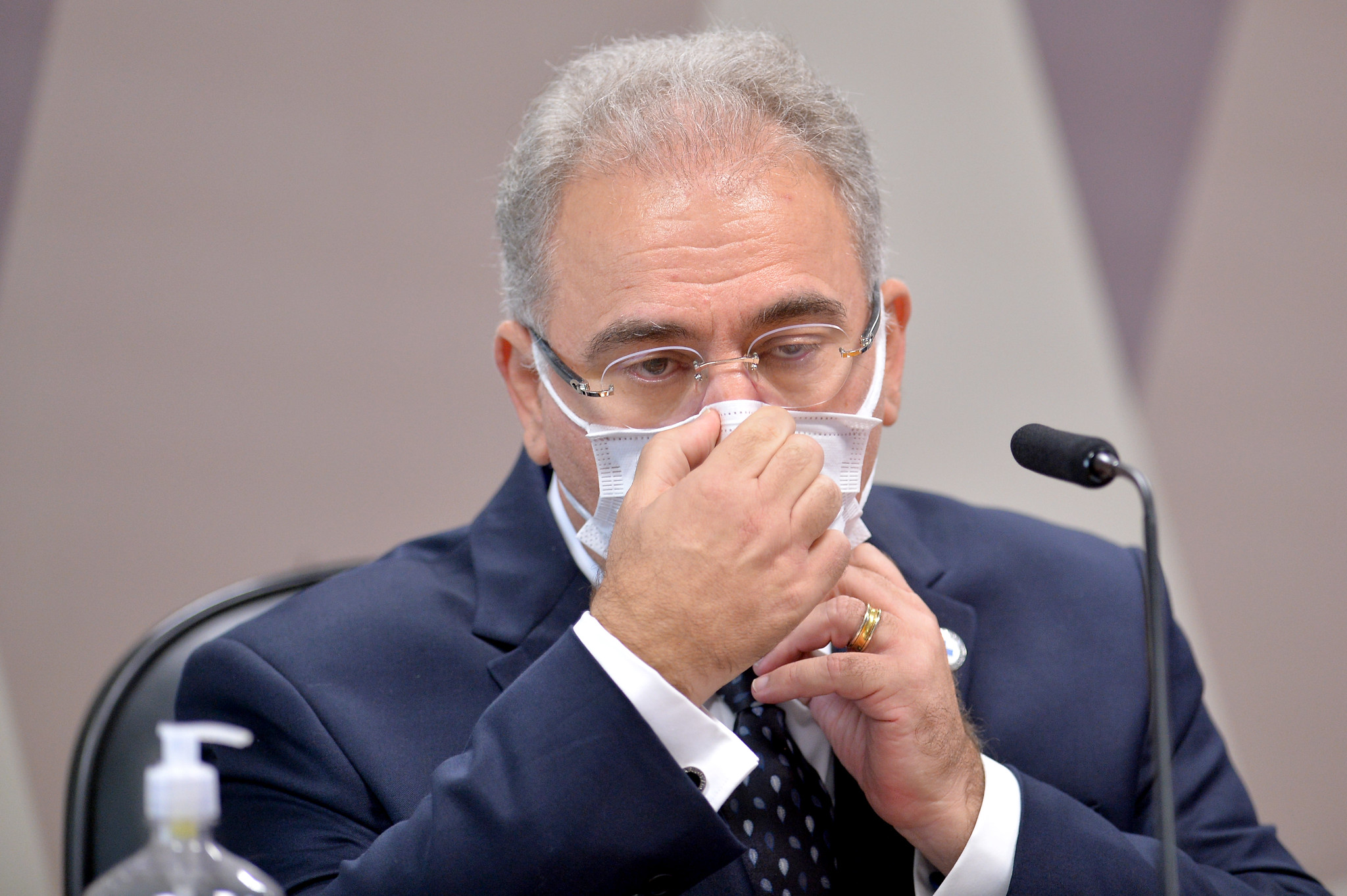 Homem de Terno Ajusta Máscara em Contexto Formal