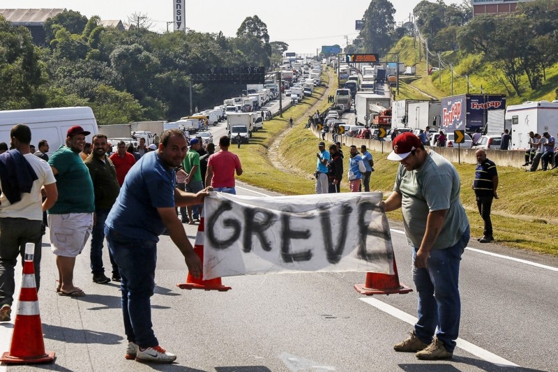 Caminhoneiro em frente ao seu veículo protestando contra o aumento abusivo dos combustíveis no Brasil.