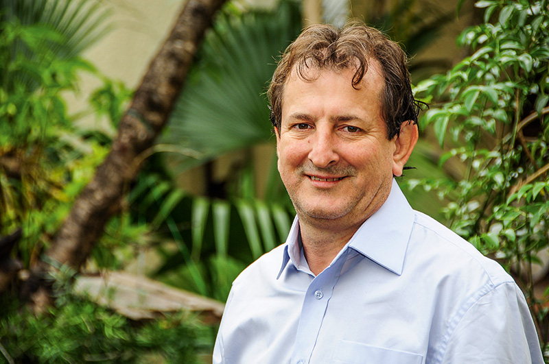 Homem sorridente em cenário natural, confiante e acessível.