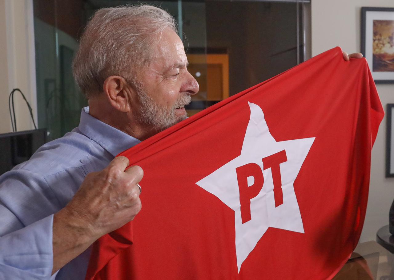 Lula exibe bandeira do PT com sorriso orgulhoso