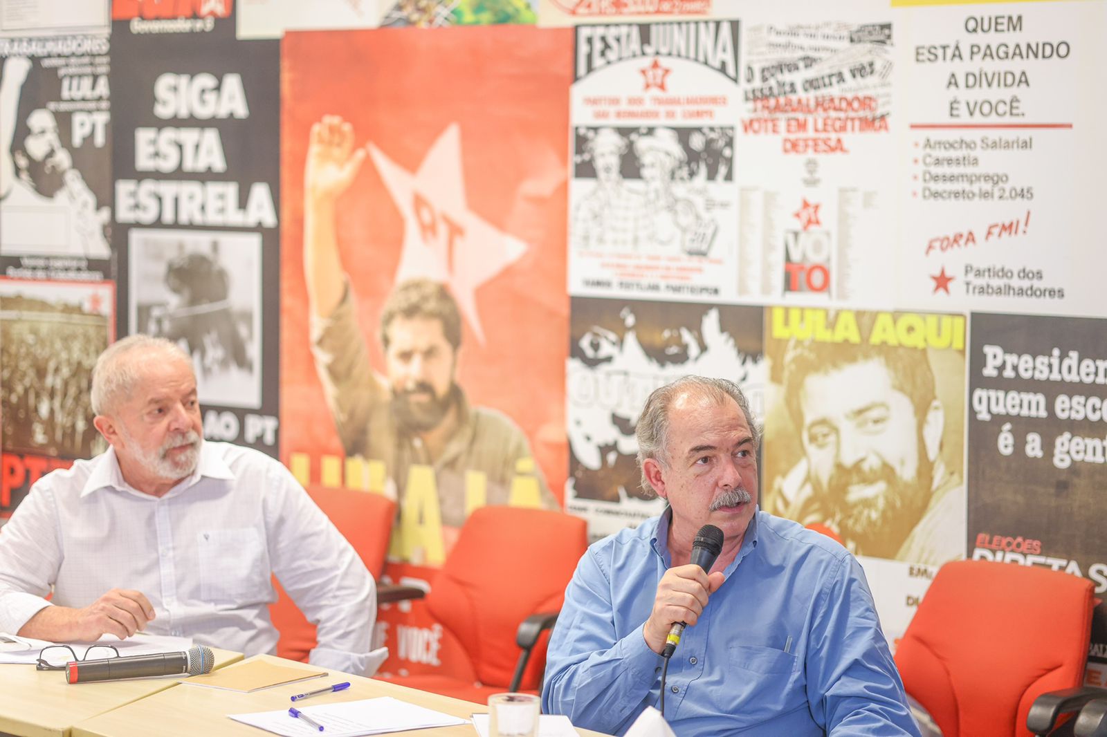 Lula e militantes em encontro político com cartazes históricos