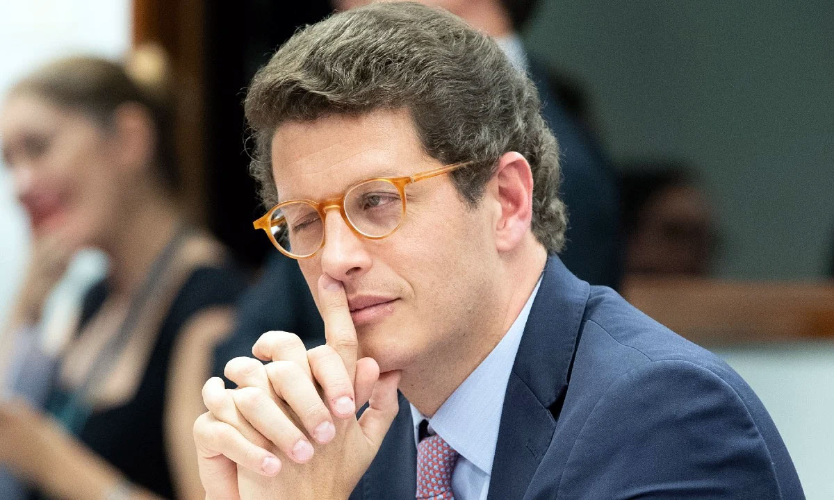 Homem de Óculos em Gesto de Silêncio e Reflexão