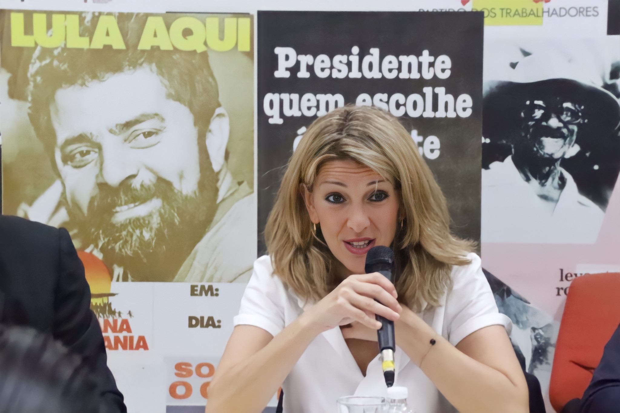 Mulher em discurso político com cartazes do PT e Lula