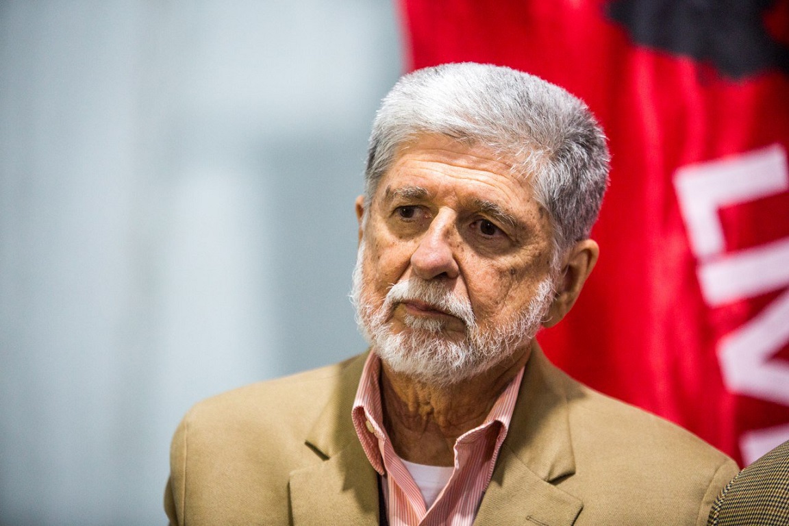 Homem Sênior Contemplativo com Fundo Político Vermelho