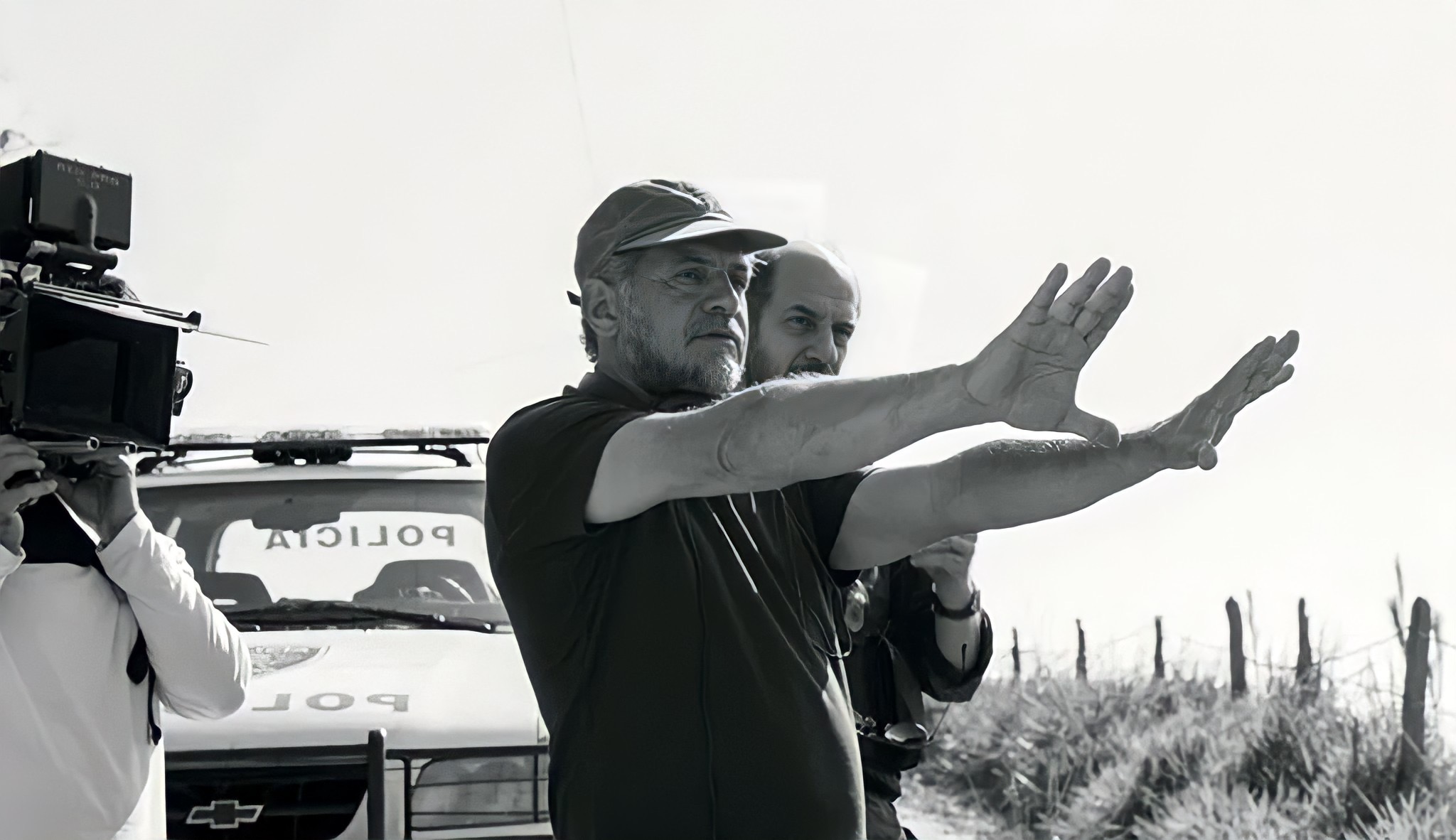 Diretor Gesticula em Set de Filmagem com Carro de Polícia